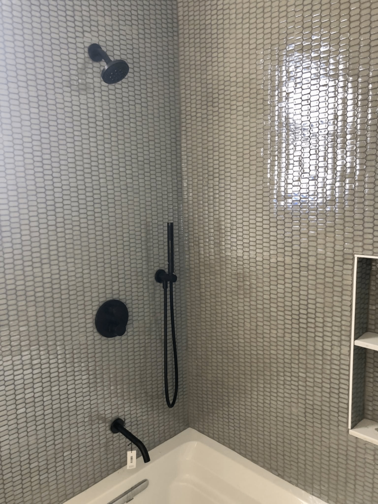 Gray penny tile tub surround with matte black fixtures