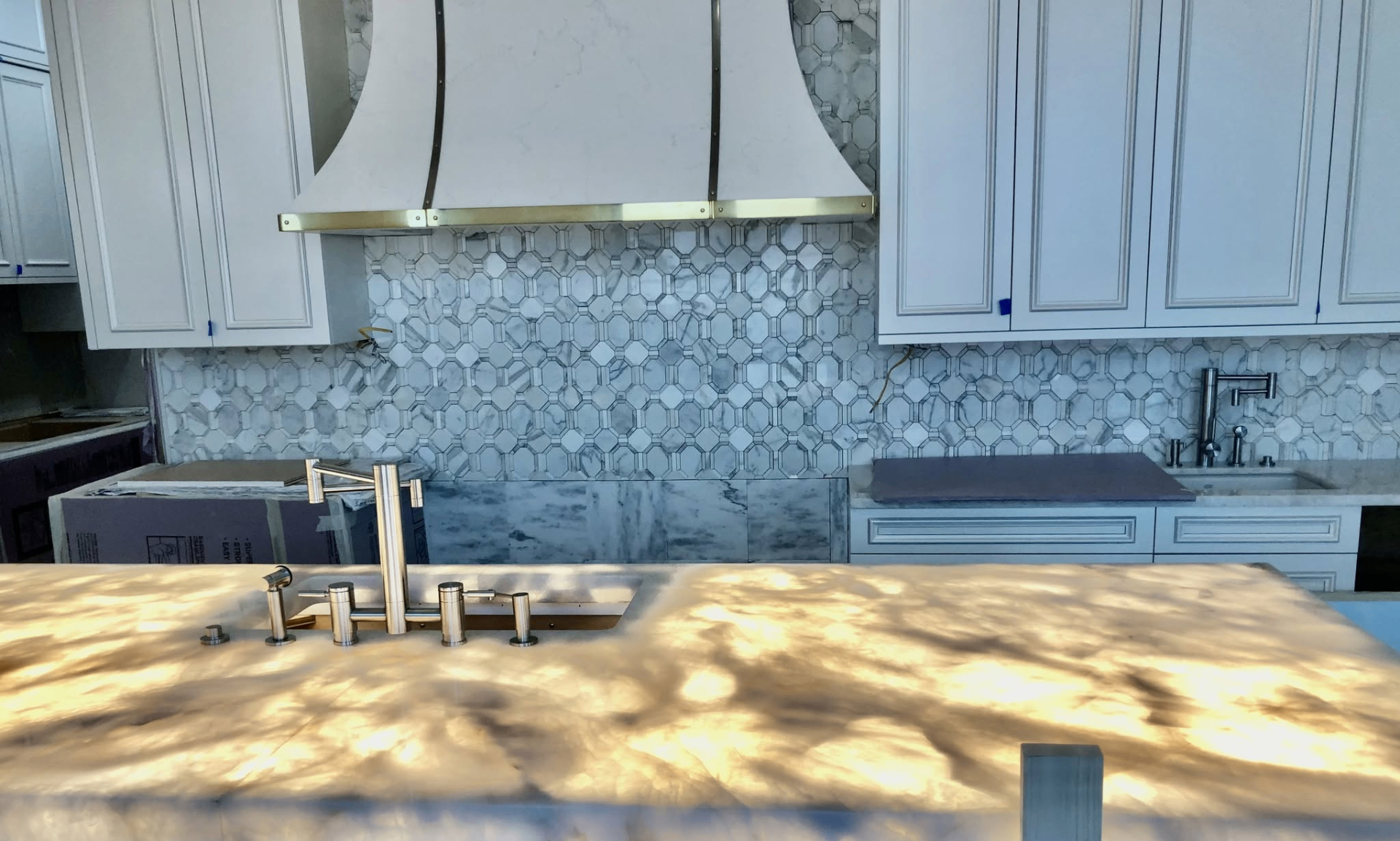 Kitchen backsplash with geometric stone-look tile behind custom hood