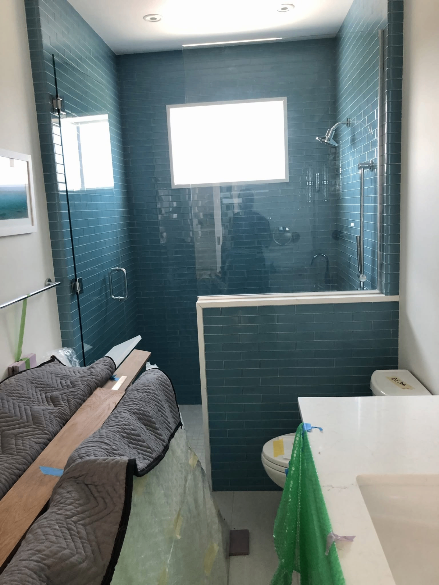 Blue subway tile shower installation with frameless glass enclosure